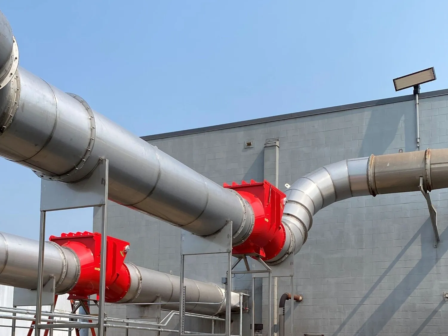 Two red Boss high-speed abort gates on large-diameter outdoor ducting carried on steel supports.